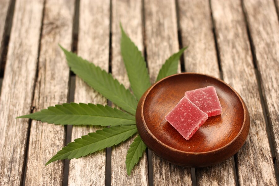 a picture of edible cannabis infused gummies in a plate next to a hemp plant